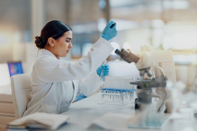 female scientist adding liquid to beakers